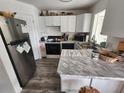 Efficient kitchen featuring stainless steel refrigerator, marble countertops, and ample white cabinetry at 4158 Tamiami Trl # U4, Port Charlotte, FL 33952