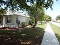 Sidewalk view of a white stucco home with well-maintained landscaping and mature trees in a peaceful neighborhood at 500 Winwood Ct, Port Charlotte, FL 33954