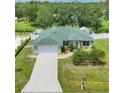 Aerial view of a one-story home with a green roof, a driveway, and a lush green lawn at 7280 Muncey Rd, North Port, FL 34291