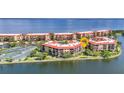 Scenic aerial view of waterfront condos surrounded by water, tennis courts, and mature trees at 90 Vivante Blvd # 202, Punta Gorda, FL 33950
