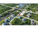 Aerial view of a home situated near a canal, surrounded by lush greenery and neighboring houses at 13406 Chenille Dr, Port Charlotte, FL 33981