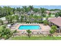 Aerial view of a community pool with lounge chairs and lush tropical landscaping at 15261 Mille Fiore Blvd, Port Charlotte, FL 33953