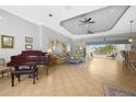 Open living room features a decorative tray ceiling, tile floors and views of the pool at 15652 Havana Cir, Port Charlotte, FL 33981