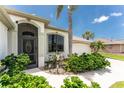 Inviting front entrance with decorative glass door, arched window and lush landscaping at 167 & 169 Marker Rd, Rotonda West, FL 33947
