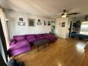 Open-concept living room with hardwood floors, fan, pictures and large purple sectional sofa at 2174 Schwalbe Way, Sarasota, FL 34235