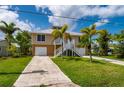Beautiful waterfront home with two car garage and stairs to the main living level and lush tropical landscaping at 24261 Captain Kidd Blvd, Punta Gorda, FL 33955