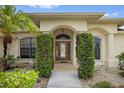 Front entrance with arched doorway, decorative glass door, and manicured bushes adding privacy and curb appeal at 264 Rotonda N Blvd, Rotonda West, FL 33947