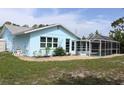 The back of the blue home features a screened in pool and landscaped gravel at 6689 Gasparilla Pines Blvd, Englewood, FL 34224
