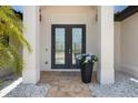 Elegant glass double-door entrance with stone landscaping, and columns creating an inviting first impression at 8081 Dimstead St, Port Charlotte, FL 33981