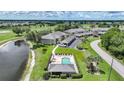 Community aerial view featuring a pool, nearby lake, and multiple condos with manicured lawns at 1375 Saxony Cir # 124, Punta Gorda, FL 33983