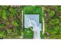 Aerial view of a home highlighting the roof, landscaping, and driveway, surrounded by green space at 14520 Edna Cir, Port Charlotte, FL 33981