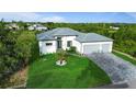 Bright exterior showcasing a modern home, well-kept lawn, and a driveway leading to a two-car garage at 14520 Edna Cir, Port Charlotte, FL 33981
