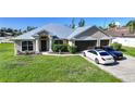 Attractive single-story home featuring a metal roof, manicured landscaping, and a three-car garage at 15117 Lyneburg Ave, Port Charlotte, FL 33981