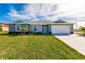 Beautiful gray home featuring a well-manicured lawn, manicured landscaping, and a two-car garage at 16403 Perdida Ct, Punta Gorda, FL 33955