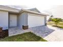 Close-up of a gray home featuring a two-car garage, entryway, and well-maintained landscaping at 16403 Perdida Ct, Punta Gorda, FL 33955