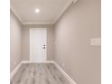 Inviting hallway featuring modern gray wood-look floors and neutral-toned walls with white trim and a front door at 16403 Perdida Ct, Punta Gorda, FL 33955