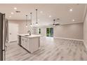 Open-concept kitchen and living area with a kitchen island, stainless steel appliances, and gray wood-look flooring at 16403 Perdida Ct, Punta Gorda, FL 33955