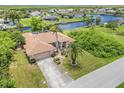 Aerial view of the property with a canal view, a screened lanai, lush greenery, and a long driveway at 17125 Canary Ln, Port Charlotte, FL 33948