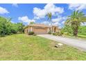 Charming single-story home with lush landscaping, mature palm trees, and a well-maintained lawn under a sunny, blue sky at 17125 Canary Ln, Port Charlotte, FL 33948