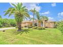 Charming single-story home with lush landscaping, mature palm trees, and a well-maintained lawn under a sunny, blue sky at 17125 Canary Ln, Port Charlotte, FL 33948
