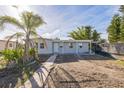 Charming single-story home featuring a partially dirt lawn and mature palm tree with dumpster in sunny neighborhood at 175 Rodgers Ne Ave, Port Charlotte, FL 33952