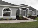 Charming single-story home featuring a well-manicured lawn, arched windows, and a screened-in entryway at 23167 Turnbull Ave, Port Charlotte, FL 33954