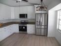 Modern kitchen featuring stainless steel appliances, white cabinets, granite countertops, and wood grain flooring at 23167 Turnbull Ave, Port Charlotte, FL 33954