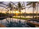 Inviting screened-in pool offers stunning sunset views over the peaceful lake and palm trees at 4334 Corso Venetia Blvd, Venice, FL 34293