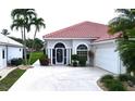 Inviting home front featuring a white tile roof, double-door entry, manicured hedges and palm trees at 10214 Arrowhead Dr, Punta Gorda, FL 33955