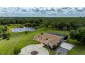 Aerial view of an estate with a circular driveway, expansive lawn, screened lanai, and picturesque lake at 10810 Wheeler Pl, Punta Gorda, FL 33950
