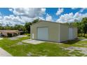 Large metal building with two roll-up doors, complemented by a home, and green lawn at 10810 Wheeler Pl, Punta Gorda, FL 33950