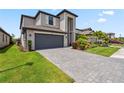 Beautiful two-story home showcasing lush landscaping, a gray brick driveway, and a large two-car garage at 11105 Balfour E St, Venice, FL 34293