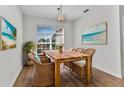 Bright dining room with a wooden table, four wicker chairs, beach artwork, hardwood floors and natural light at 1605 Palace Ct, Punta Gorda, FL 33980