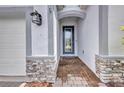 Close-up of the front door entrance showing stone and brick accents, covered entryway at 16848 Canopy Garden Dr, Port Charlotte, FL 33953