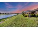Expansive backyard with lush green grass leading to a serene lake and screened lanai at 1775 Scarlett Ave, North Port, FL 34289