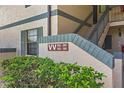 Close-up of building entrance with stairs, showing apartment numbers, textured walls, and manicured green shrubs at 19505 Quesada Ave # Vv201, Port Charlotte, FL 33948