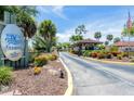 A view of the Roll's Landing entrance, featuring lush landscaping and a welcoming gatehouse, providing a secure and private feel at 23465 Harborview Rd # 214, Punta Gorda, FL 33980