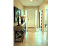 Inviting foyer featuring neutral tile flooring, console table with decorative accents, and a bright front door at 25224 Lahore Ln, Punta Gorda, FL 33983