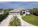 Aerial view of lovely home with lush tropical landscaping and a large concrete driveway at 25462 Shore Dr, Punta Gorda, FL 33950