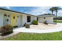 Close-up of a home's entrance featuring a bright yellow front door, lush landscaping, and a well-maintained lawn at 4051 Rock Creek Dr, Port Charlotte, FL 33948