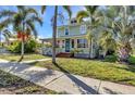 Inviting two-story home with mature palm trees, a brick walkway, and a charming front porch at 415 W Marion Ave, Punta Gorda, FL 33950