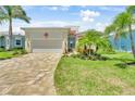 Inviting single-story home with manicured lawn, brick driveway, and a charming facade with tropical accents at 10478 Coquina Ct, Placida, FL 33946