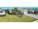 Beautiful single-story home featuring a well manicured lawn, tropical landscaping, and a brick paver driveway at 14436 Ponce De Leon Trl, Port Charlotte, FL 33981