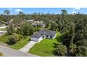 Aerial view of a modern home with a well-manicured lawn nestled among lush trees at 17156 Eugene Ave, Port Charlotte, FL 33954