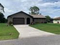 Single-story home with a long driveway and a nicely landscaped front lawn at 18094 Ackerman Ave, Port Charlotte, FL 33948