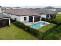 Aerial view of private backyard featuring a pool, screened-in patio, and black metal fence at 1992 Sunset Preserve Way, Port Charlotte, FL 33953