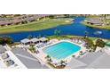 Community swimming pool, spa, and lounge area surrounded by lush landscaping and seating at 24132 Buckingham Way, Punta Gorda, FL 33980