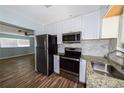 Modern kitchen featuring stainless steel appliances, granite countertops, white cabinetry, and stylish backsplash at 3085 Arrowhead Rd, Venice, FL 34293