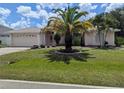 Inviting home with a lush lawn, mature palm trees, and an attached two-car garage at 388 Orlando Blvd, Port Charlotte, FL 33954
