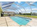 A covered screened-in pool area with lounge seating, and travertine tile overlooking the backyard and canal at 4123 Rock Creek Dr, Port Charlotte, FL 33948